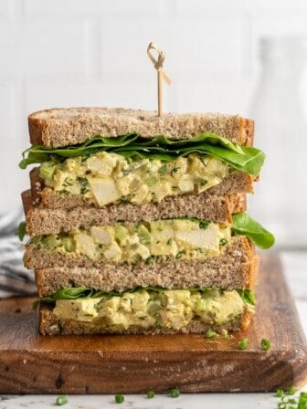 3 stacked tofu egg salad sandwiches on cutting board