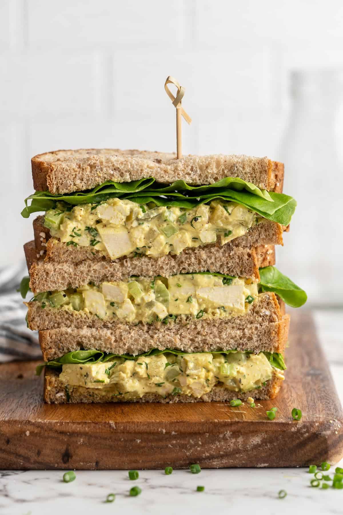 3 stacked tofu egg salad sandwiches on cutting board