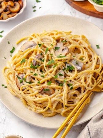 Plate of vegan pasta carbonara with fork and spoon