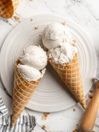 Overhead view of two vegan ice cream cones with vanilla ice cream on plate