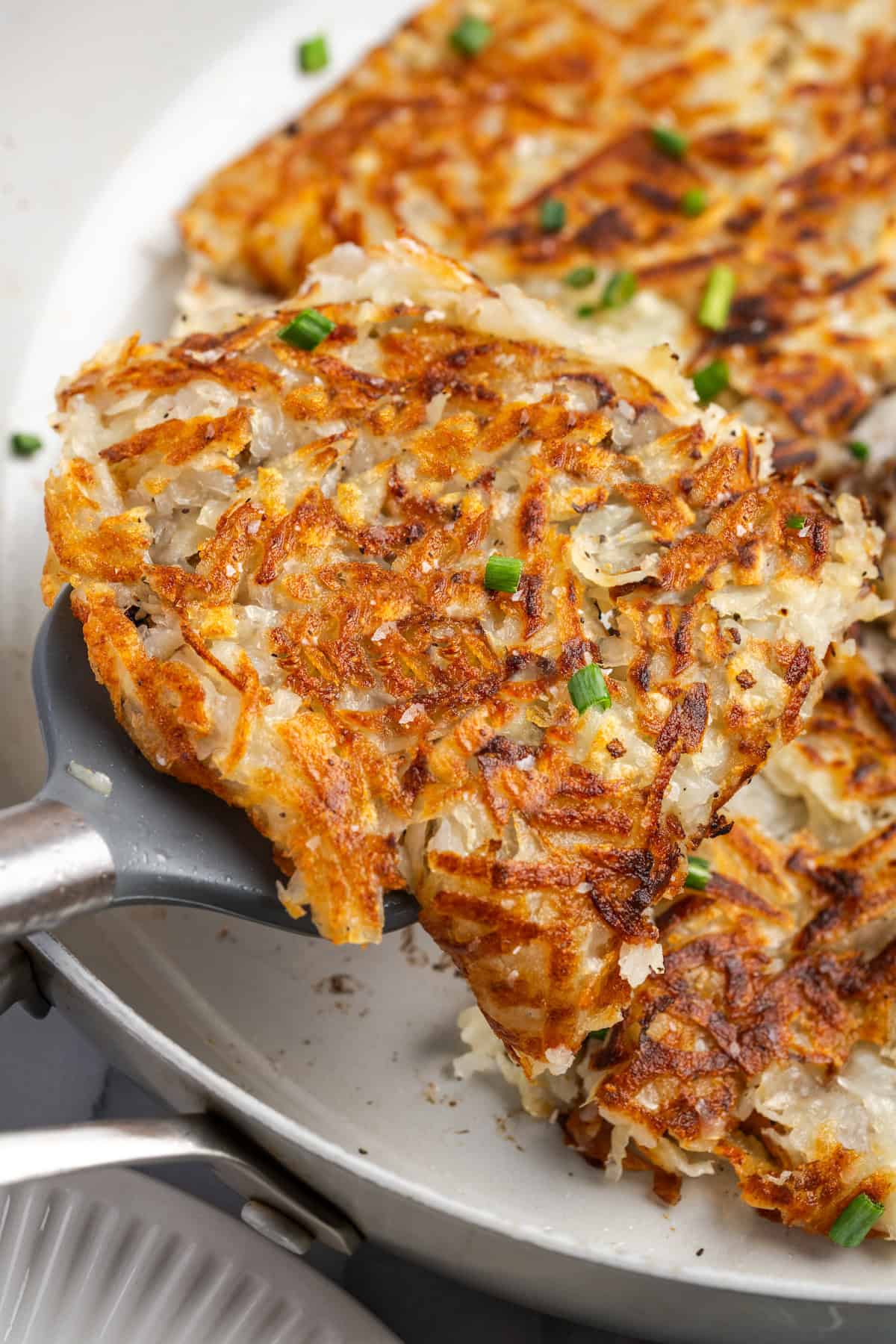 Spatula lifting hash browns from skillet