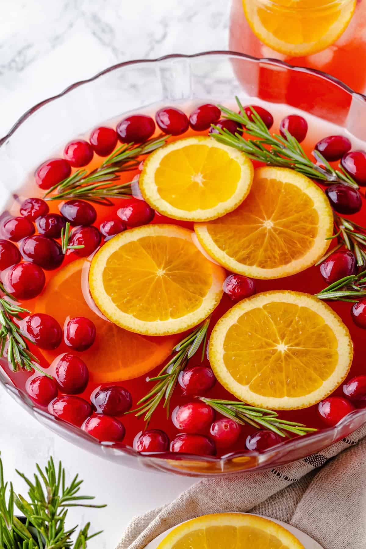 Bowl of Christmas punch with orange slices, cranberries, and rosemary