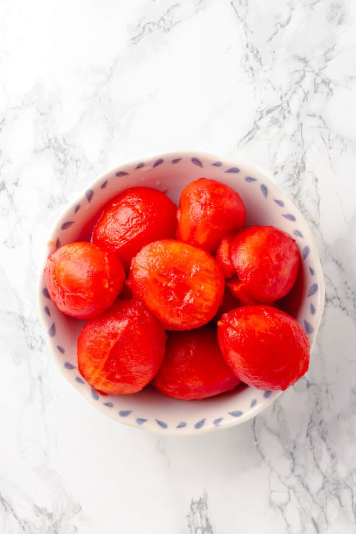 Overhead view of blanched roma tomatoes in bowl