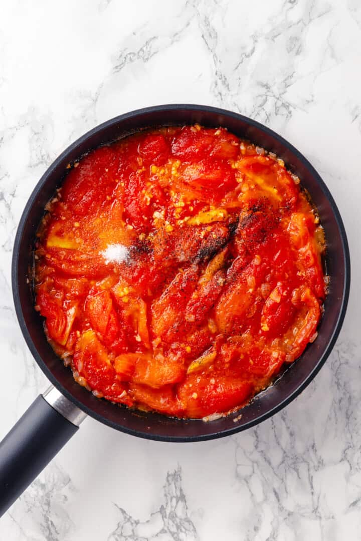 Overhead view of sugar added to pan of pomodoro sauce