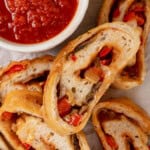 Overhead view of sliced stromboli with cup of marinara