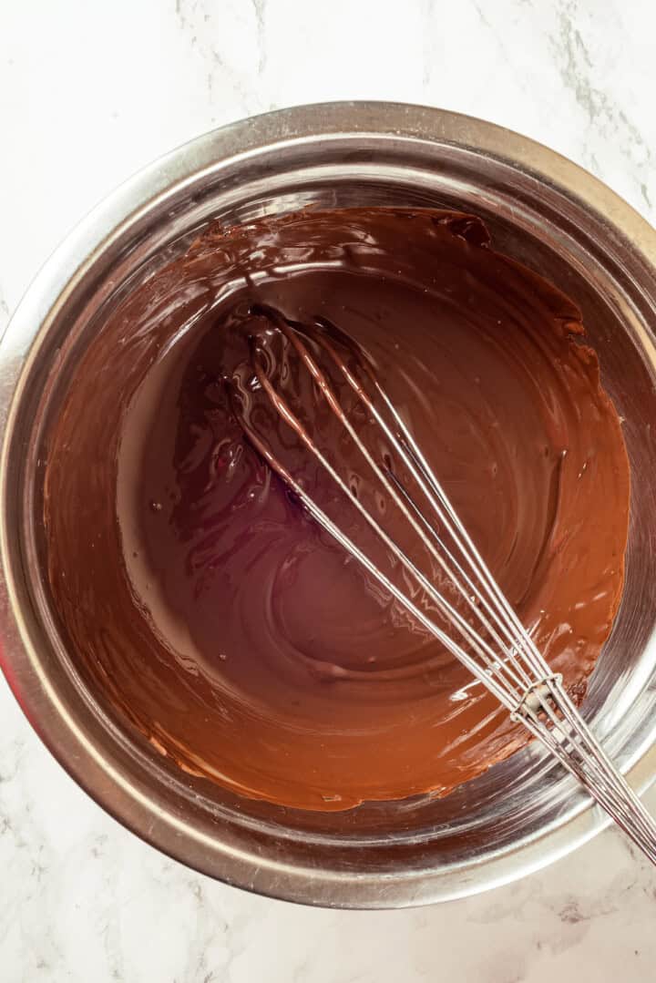 Overhead view of melted chocolate in bowl with whisk