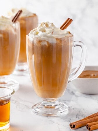 Mug of hot buttered rum with whipped cream and cinnamon stick