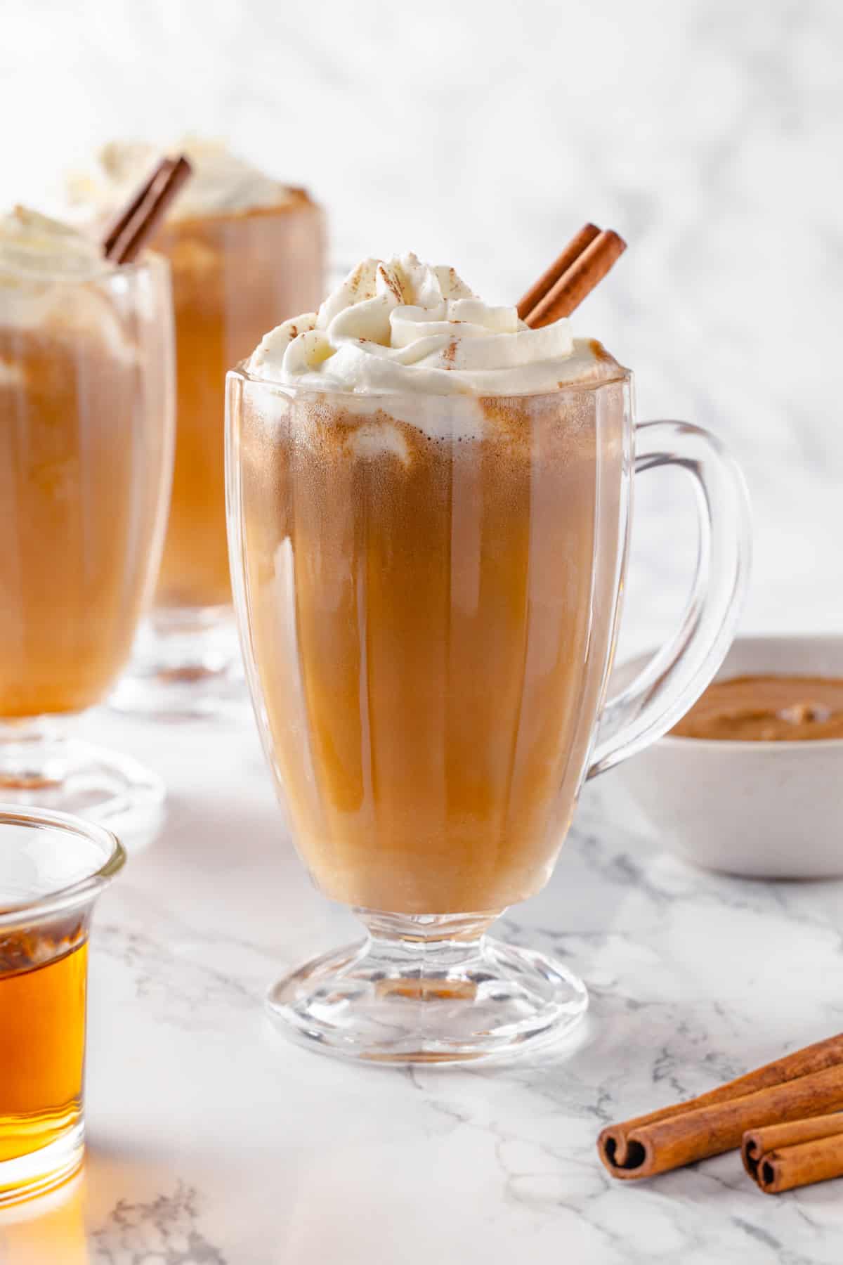 Mug of hot buttered rum with whipped cream and cinnamon stick