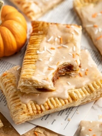 Two vegan pumpkin pop tarts stacked on top of each other, with one bitten in corner