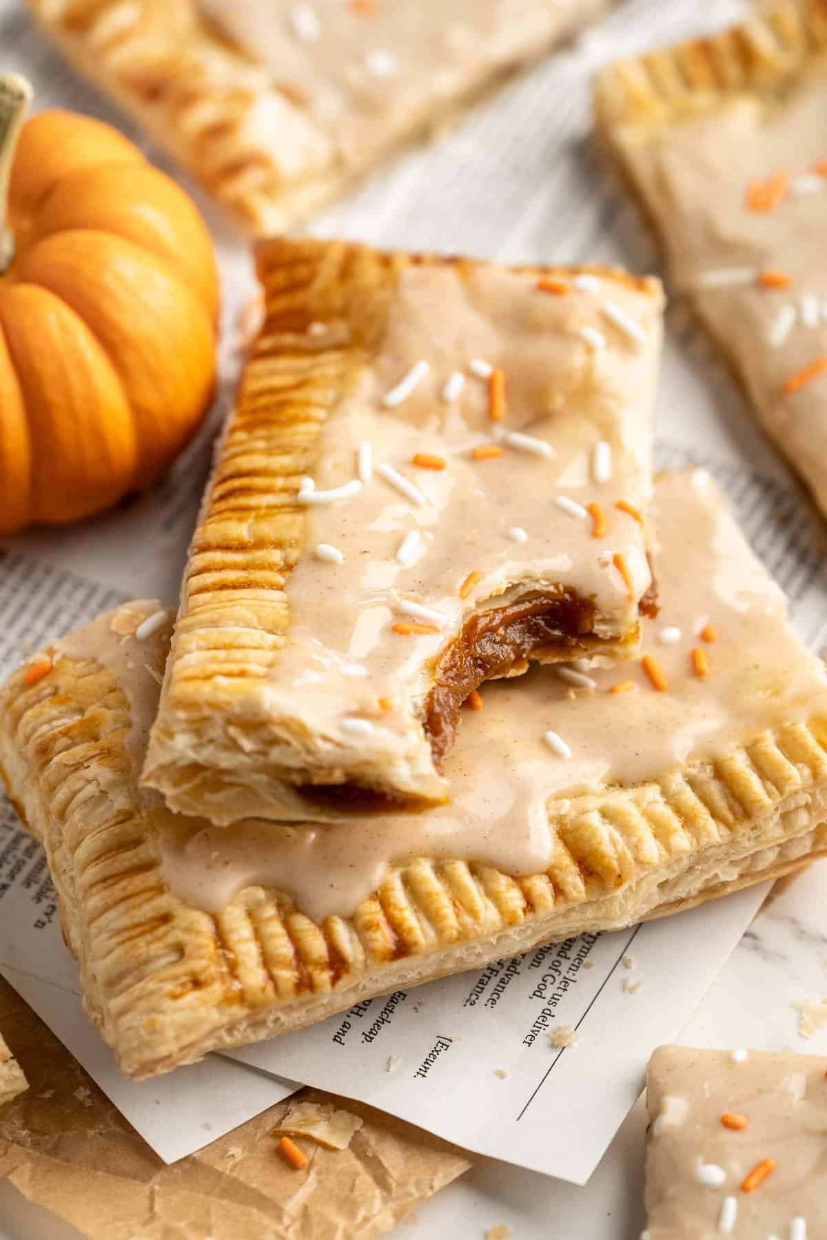 Two vegan pumpkin pop tarts stacked on top of each other, with one bitten in corner