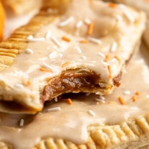 Two homemade pumpkin pop tarts stacked on top of each other with bite taken out of top to show filling