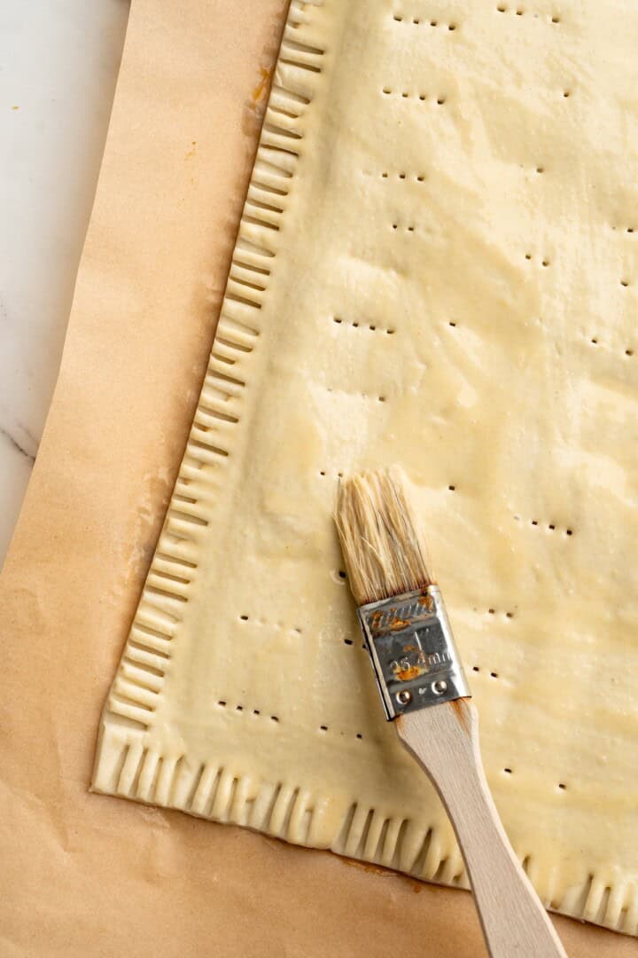 Brushing egg wash onto pumpkin pop tart