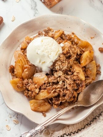 Overhead view of apple crisp in bowl with scoop of vanilla ice cream