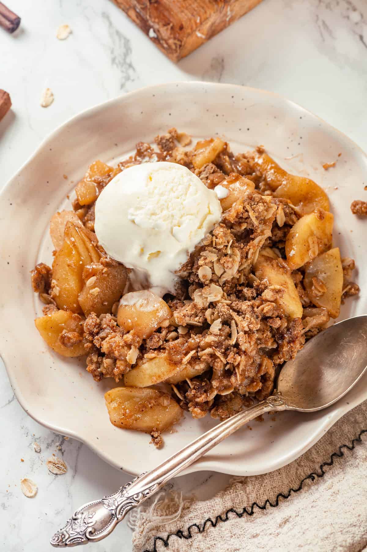 Overhead view of apple crisp in bowl with scoop of vanilla ice cream