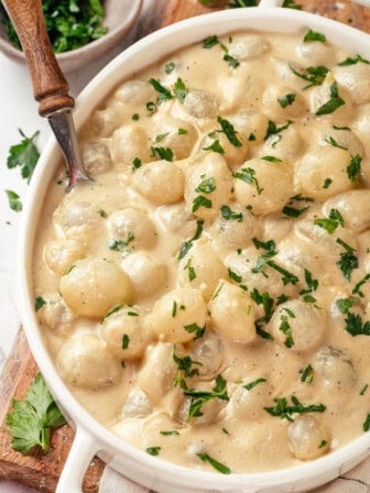 Overhead view of creamed onions in dish with spoon