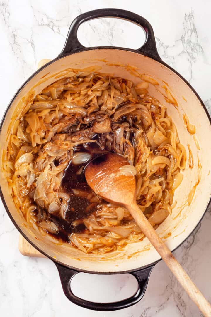 Overhead view of balsamic vinegar and wine added to pot of caramelized onions