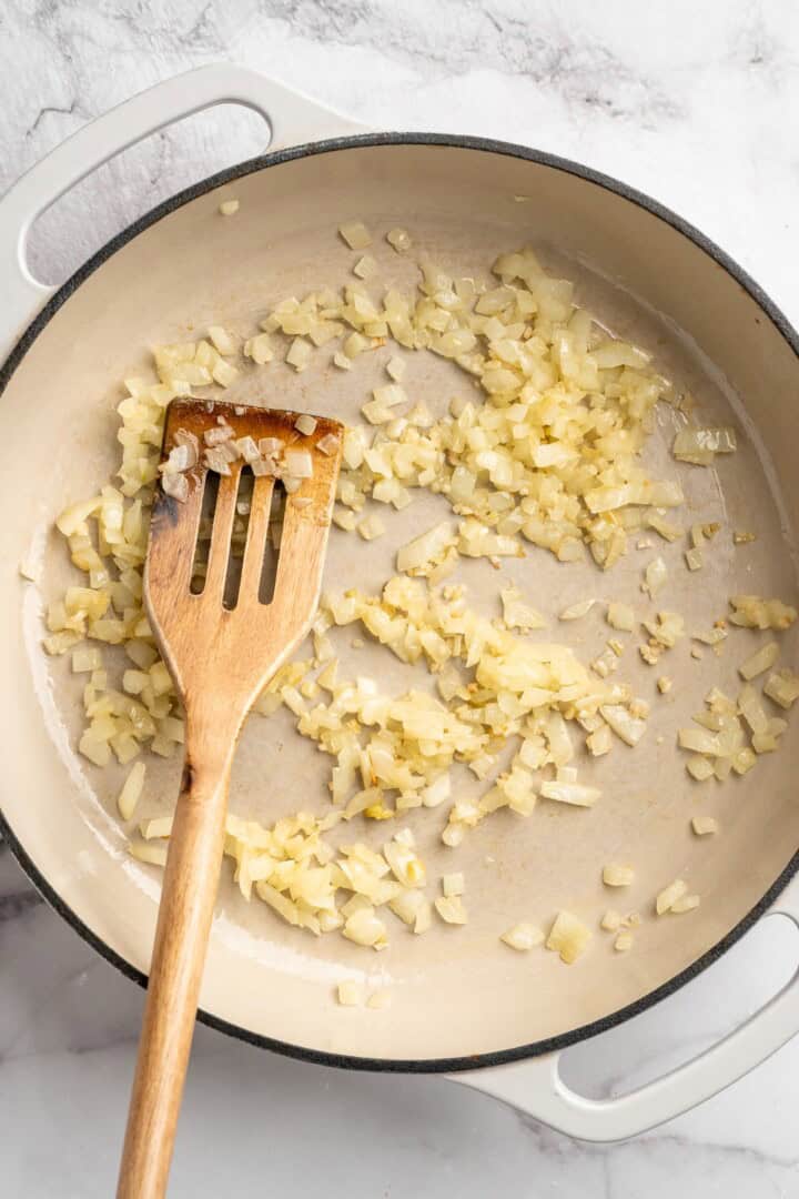 Overhead view of diced onions cooking in skillet