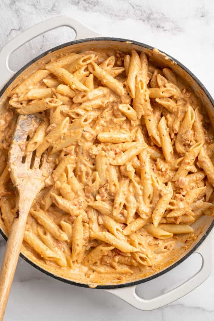 Stirring marry me pasta in skillet with slotted spoon