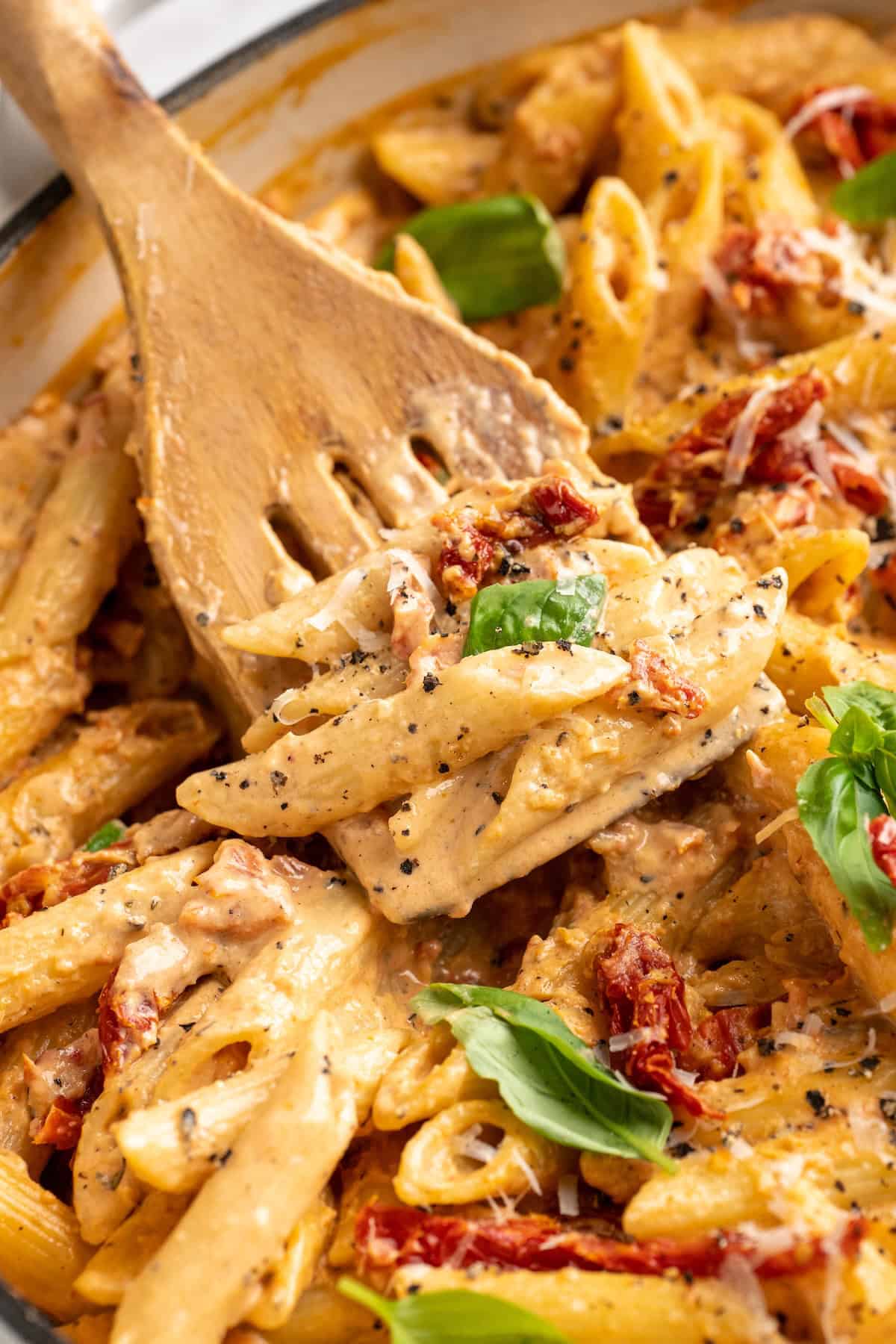 Slotted spoon stirring vegan marry me pasta in pan