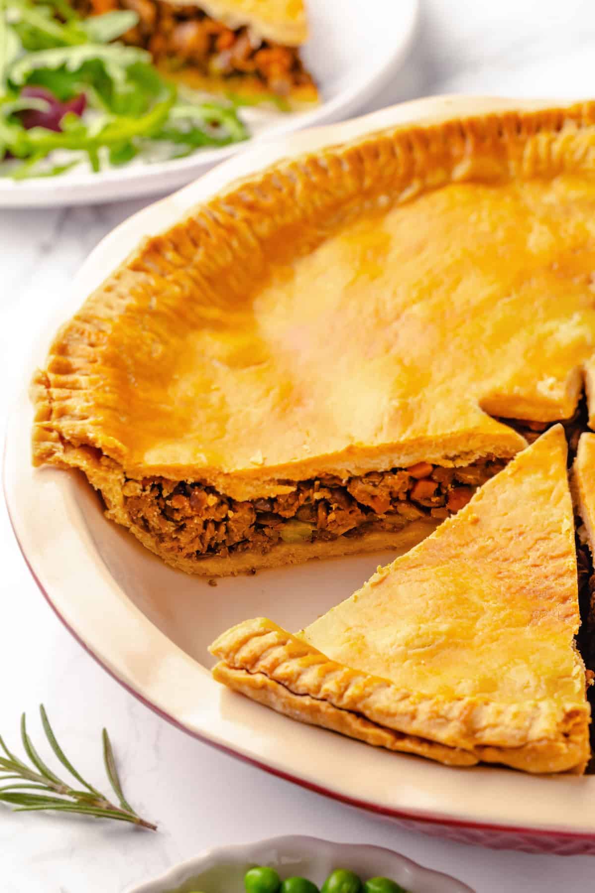 Vegan tourtière in pie pan with slice cut