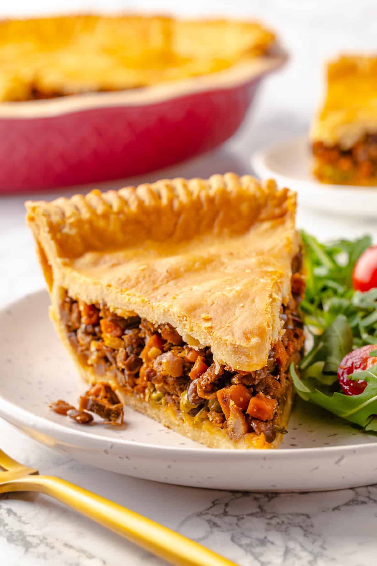 Slice of tourtière on plate with salad