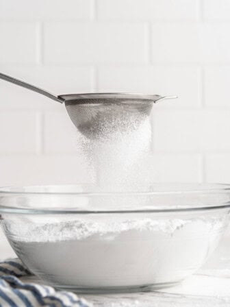 Sifting powdered sugar into bowl