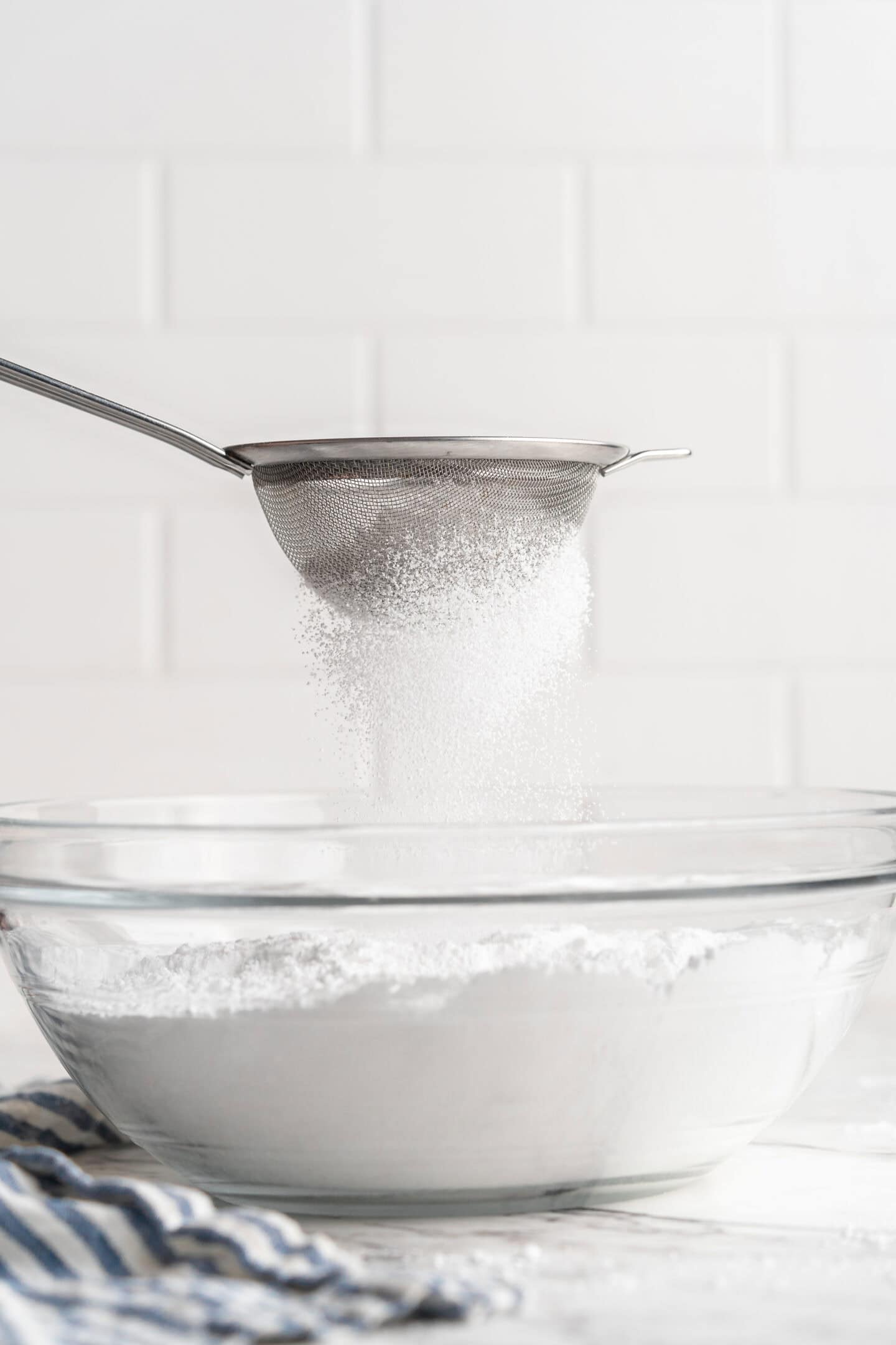 Sifting powdered sugar into bowl