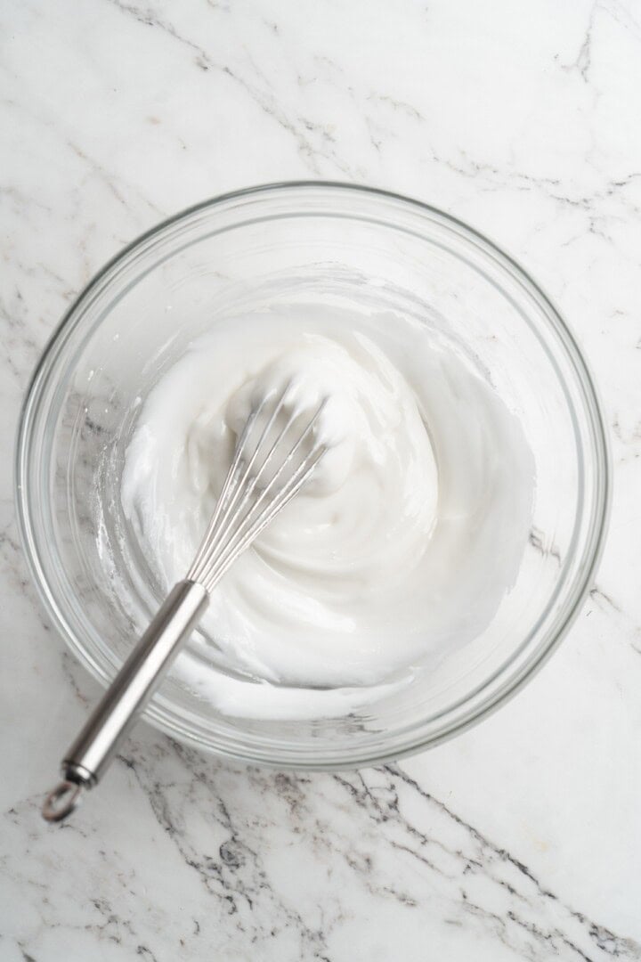 Water and powdered sugar mixed in bowl with whisk