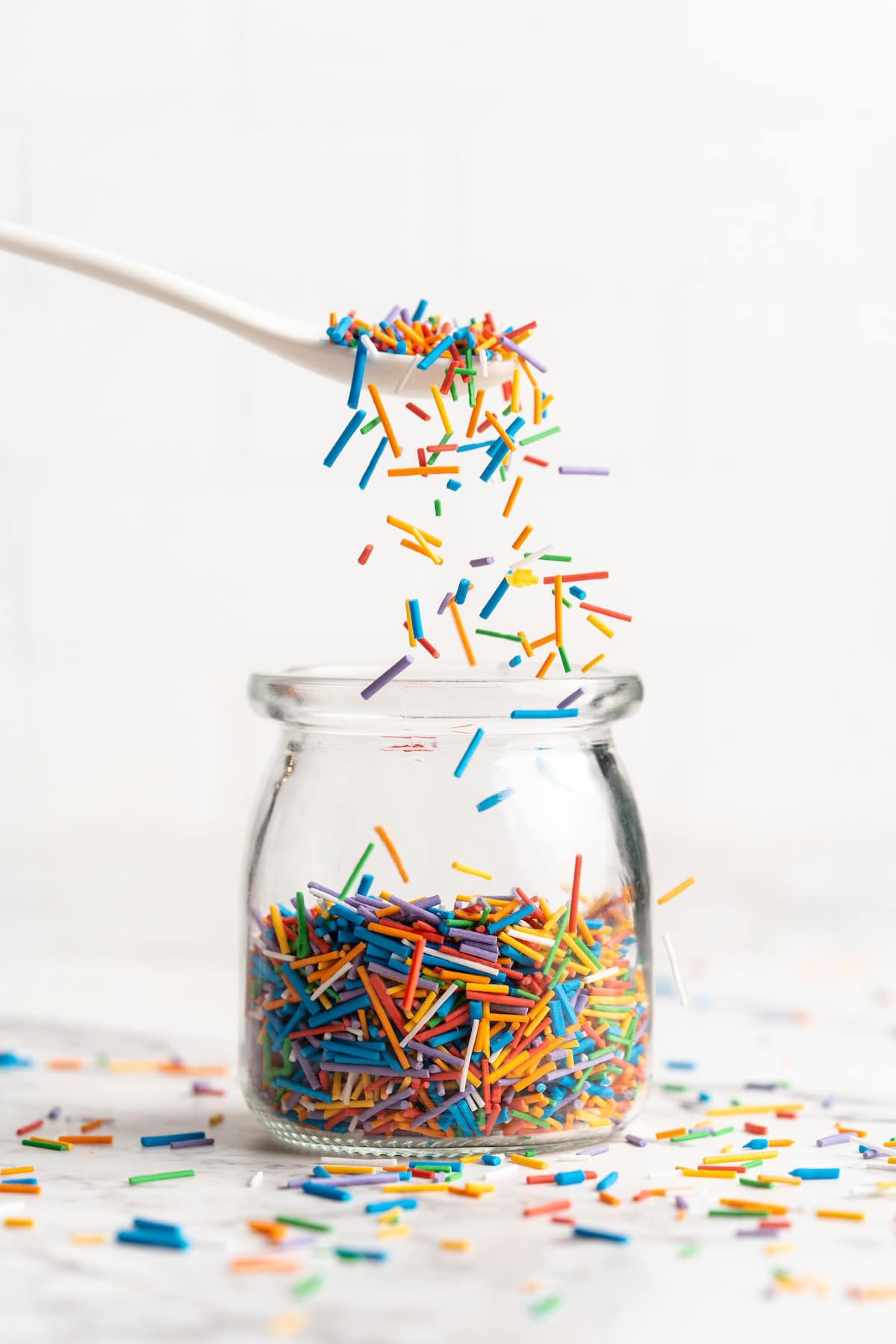 Spoonful of homemade sprinkles held over jar