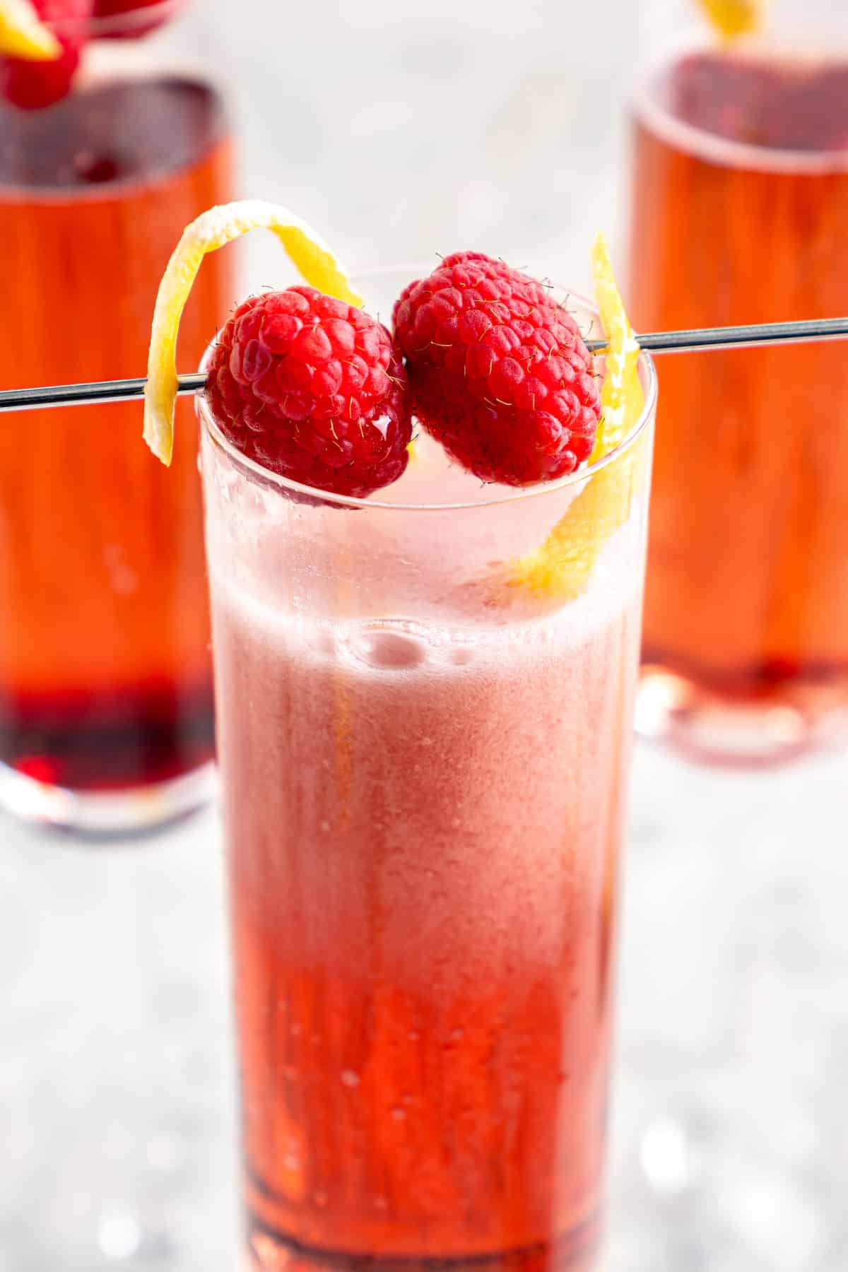 Kir royale with raspberries and lemon twist for garnish