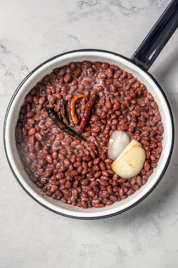 Beans in a pot with chilis and onion.