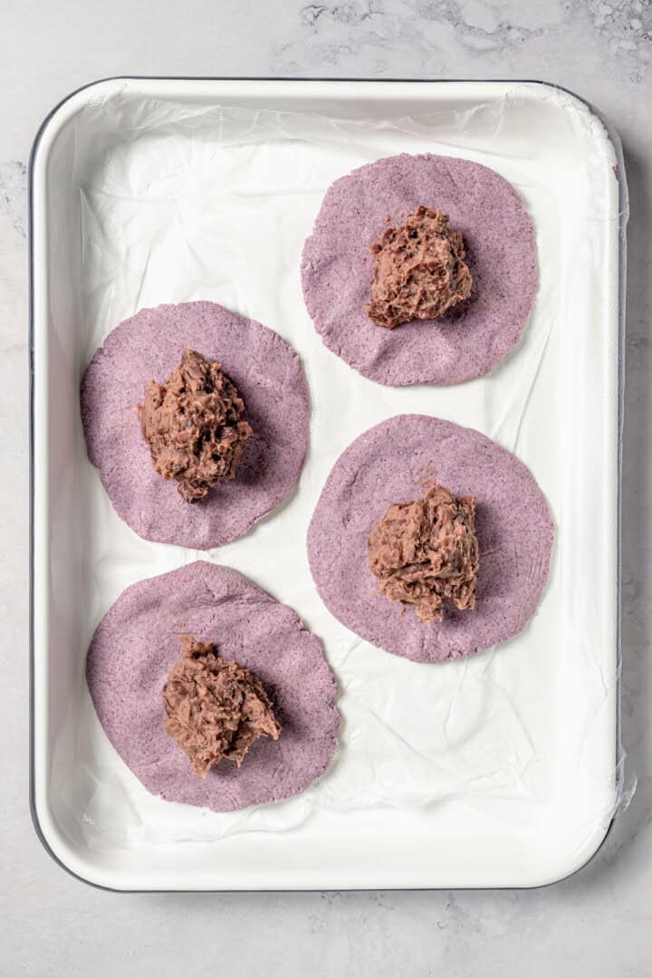 Adding bean filling to flattened masa dough.