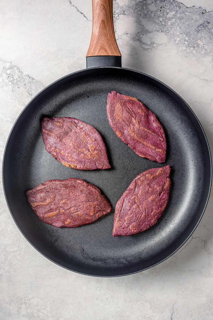 Cooking tlacoyos in a skillet.