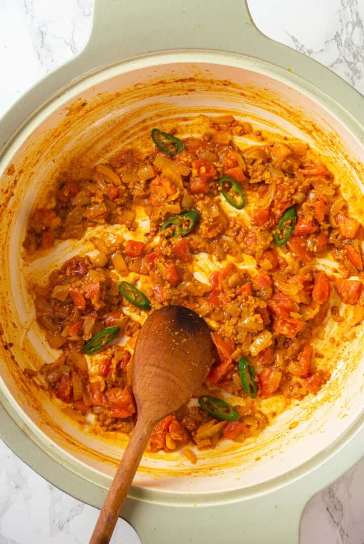 Stirring tomatoes into tadka for red lentil dal