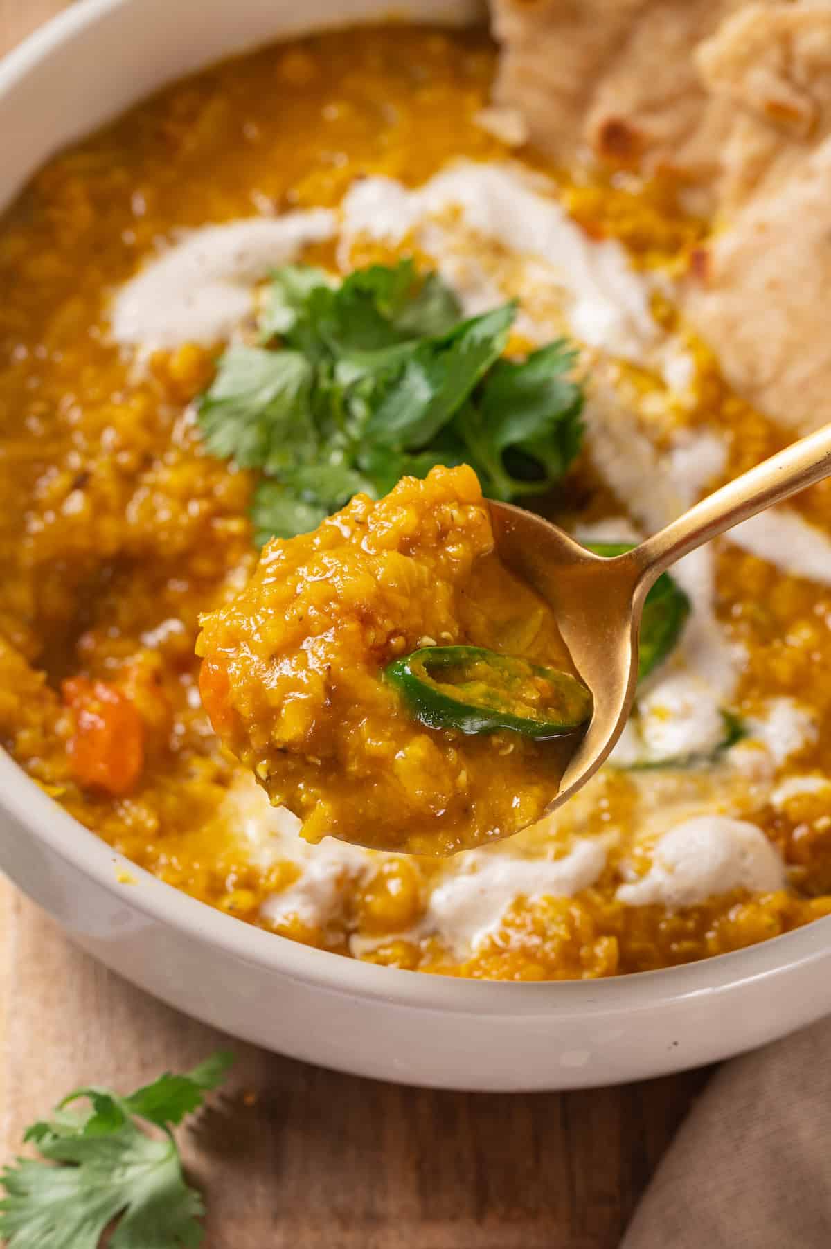 Spoonful of red lentil dal held over bowl