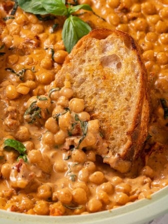 Bread dipping into bowl of marry me chickpeas