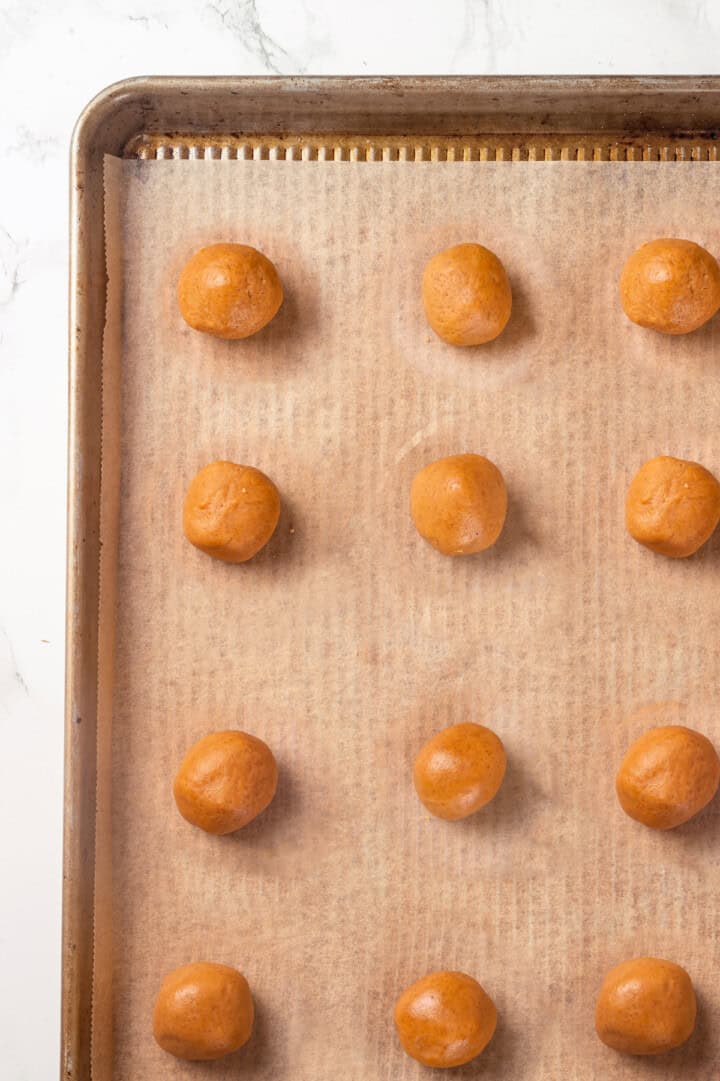 Overhead view of balls of peanut butter cookie dough on baking sheet