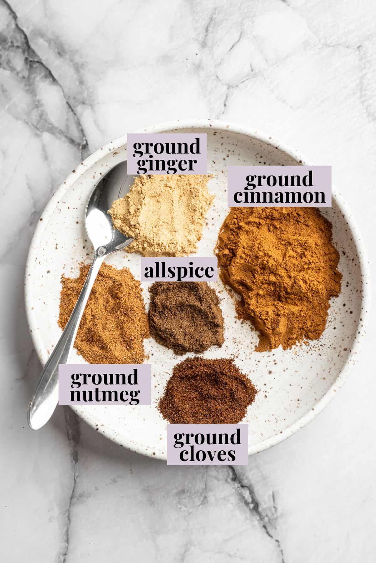 Overhead view of pumpkin pie spice ingredients in bowl with labels