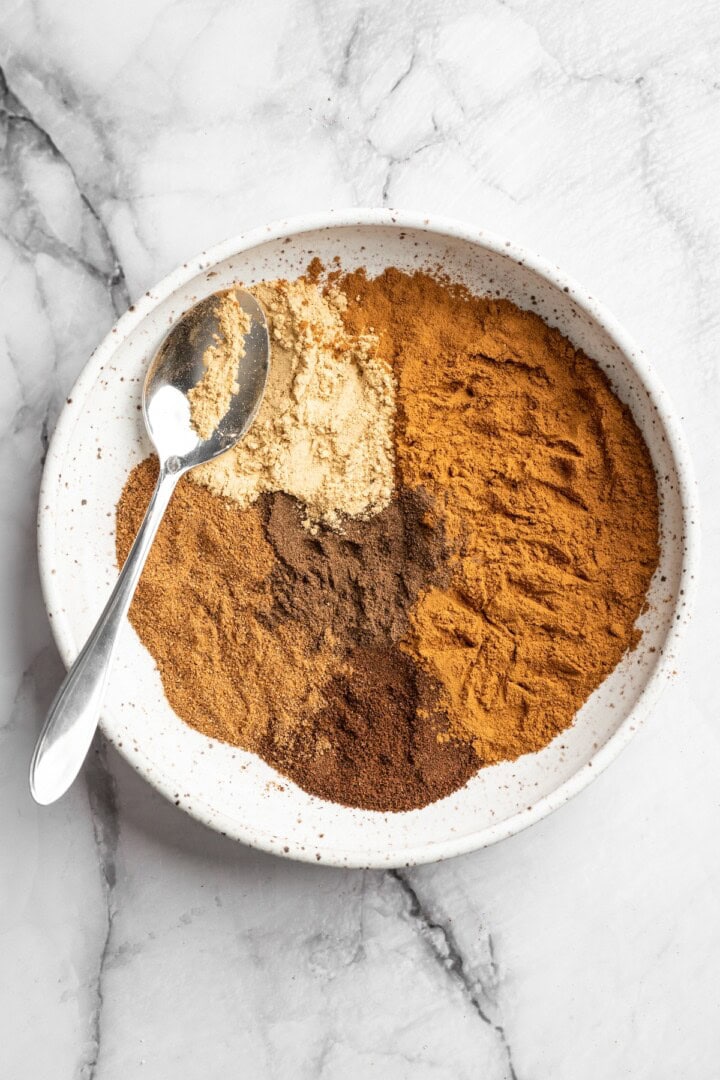 Overhead view of ingredients for pumpkin pie spice in bowl before stirring