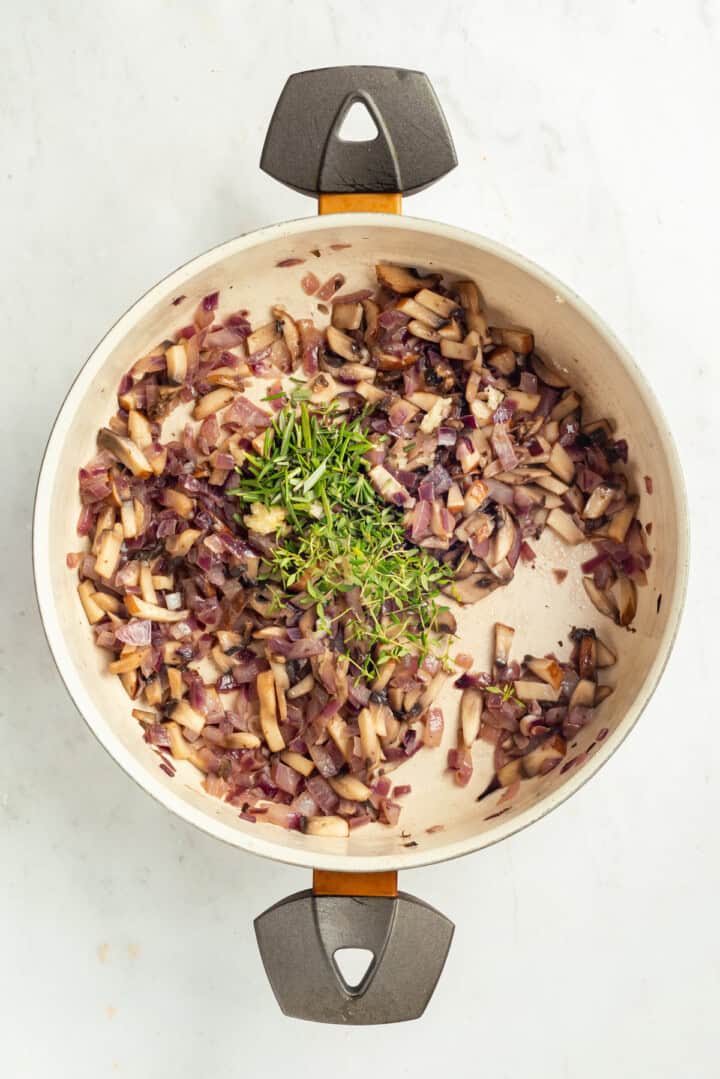 Red onion, mushrooms, and herbs in pan