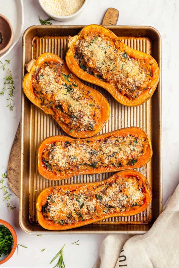 Overhead view of 4 stuffed butternut squash halves on sheet pan