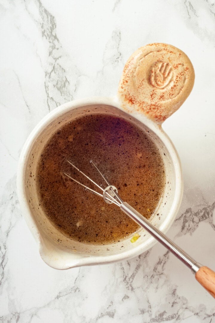 Overhead view of lemon dressing in small bowl with whisk