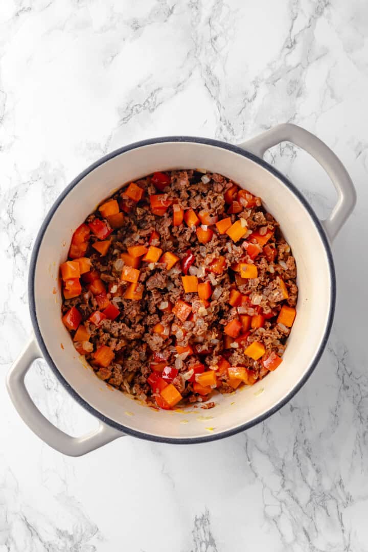 Overhead view of browned sausage and vegetables in pot