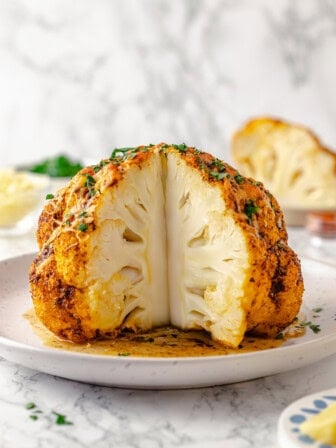 Whole roasted cauliflower on platter with wedge cut out