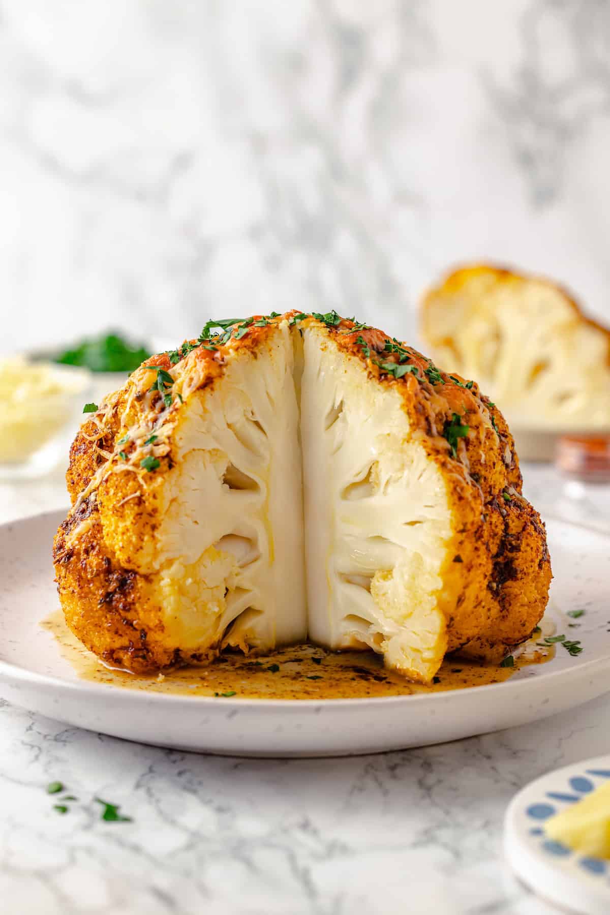 Whole roasted cauliflower on platter with wedge cut out