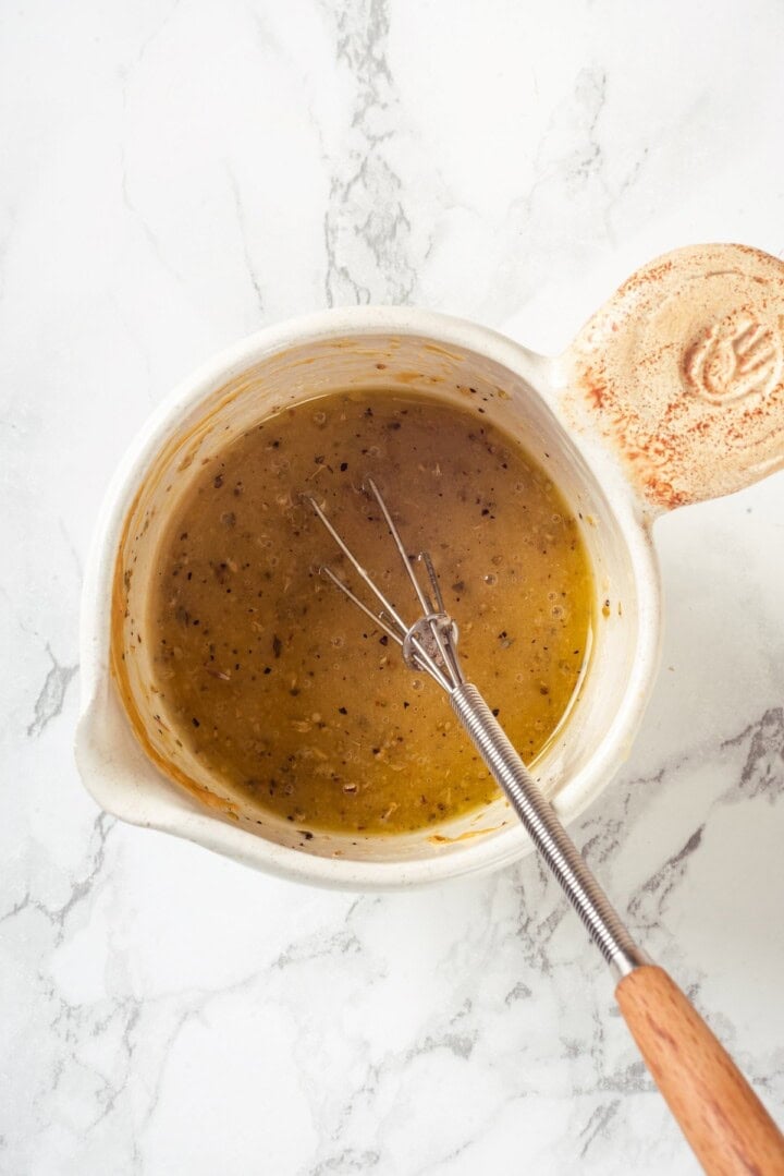 Overhead view of lemon vinaigrette in small bowl with whisk