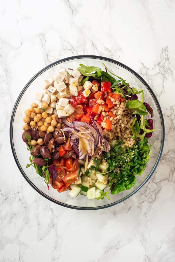 Overhead view of ingredients for farro salad in bowl before tossing