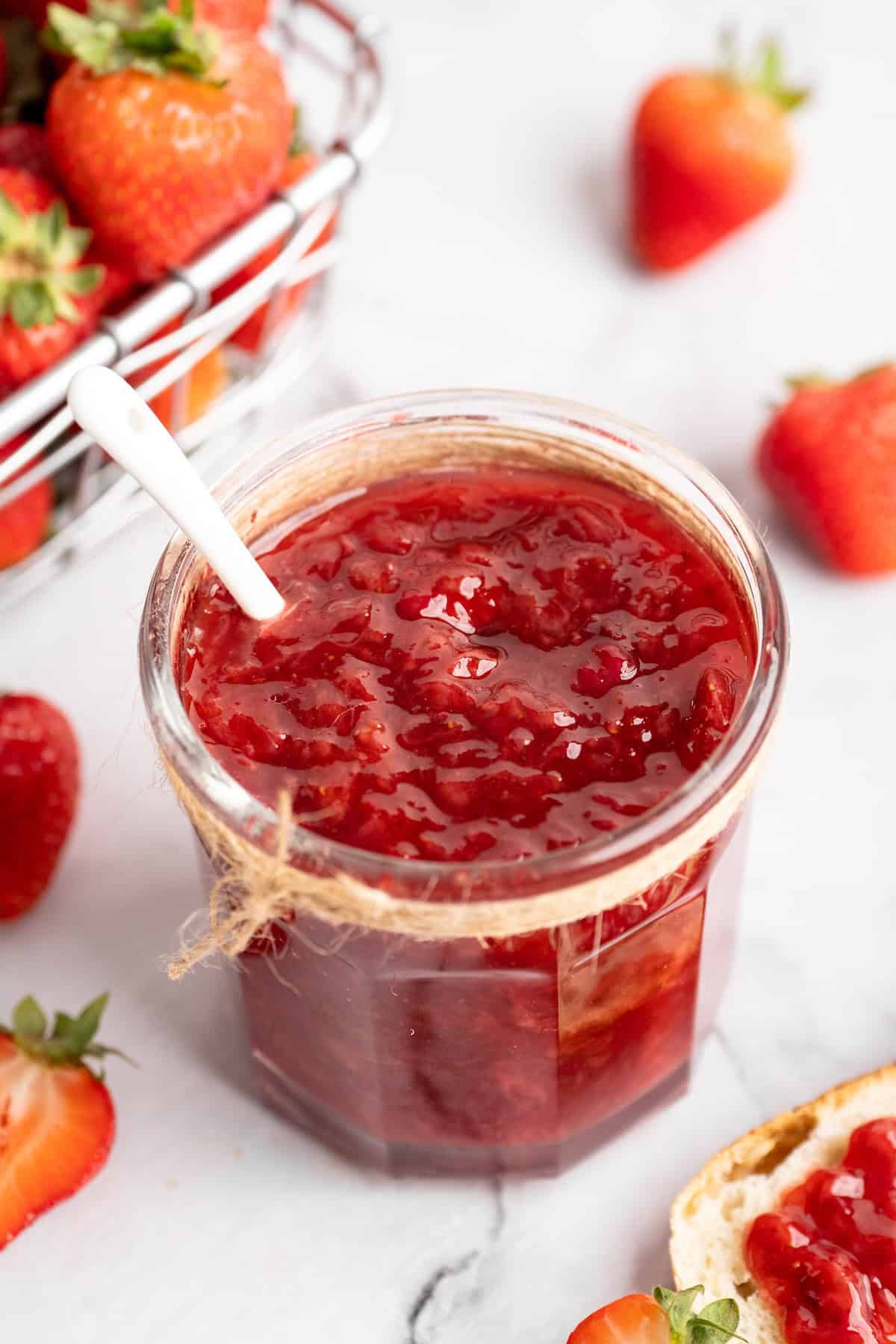 Top-down view of strawberry jam in jar with spoon