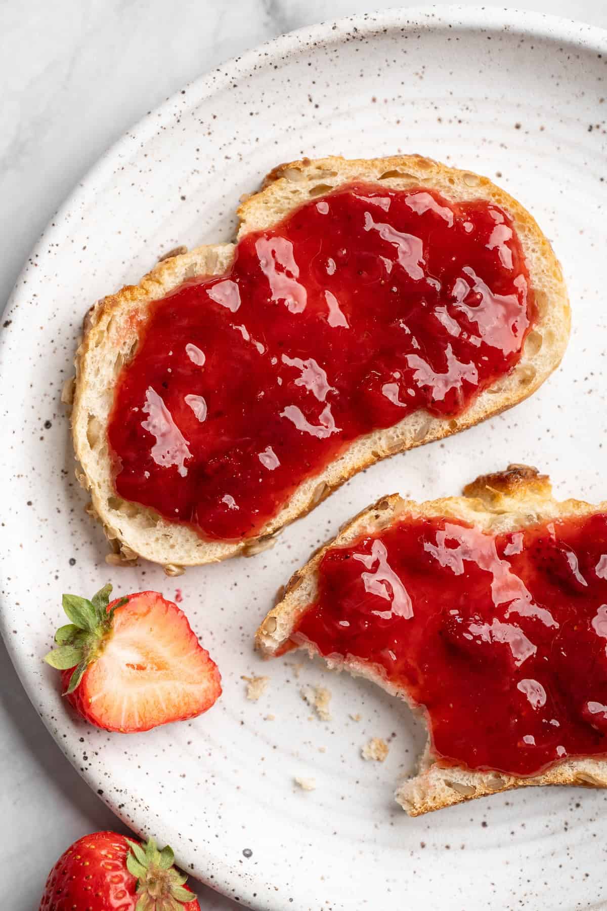 Overhead view of homemade strawberry jam spread onto two pieces of bread