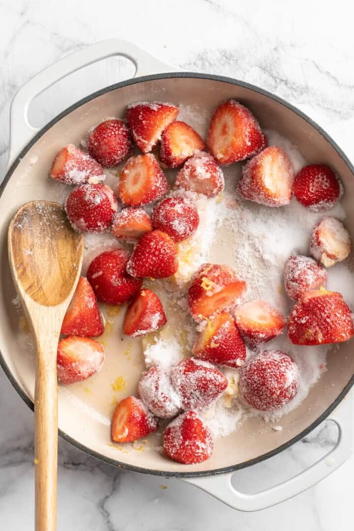 Strawberries, lemon juice and zest, and sugar in pot with wooden spoon